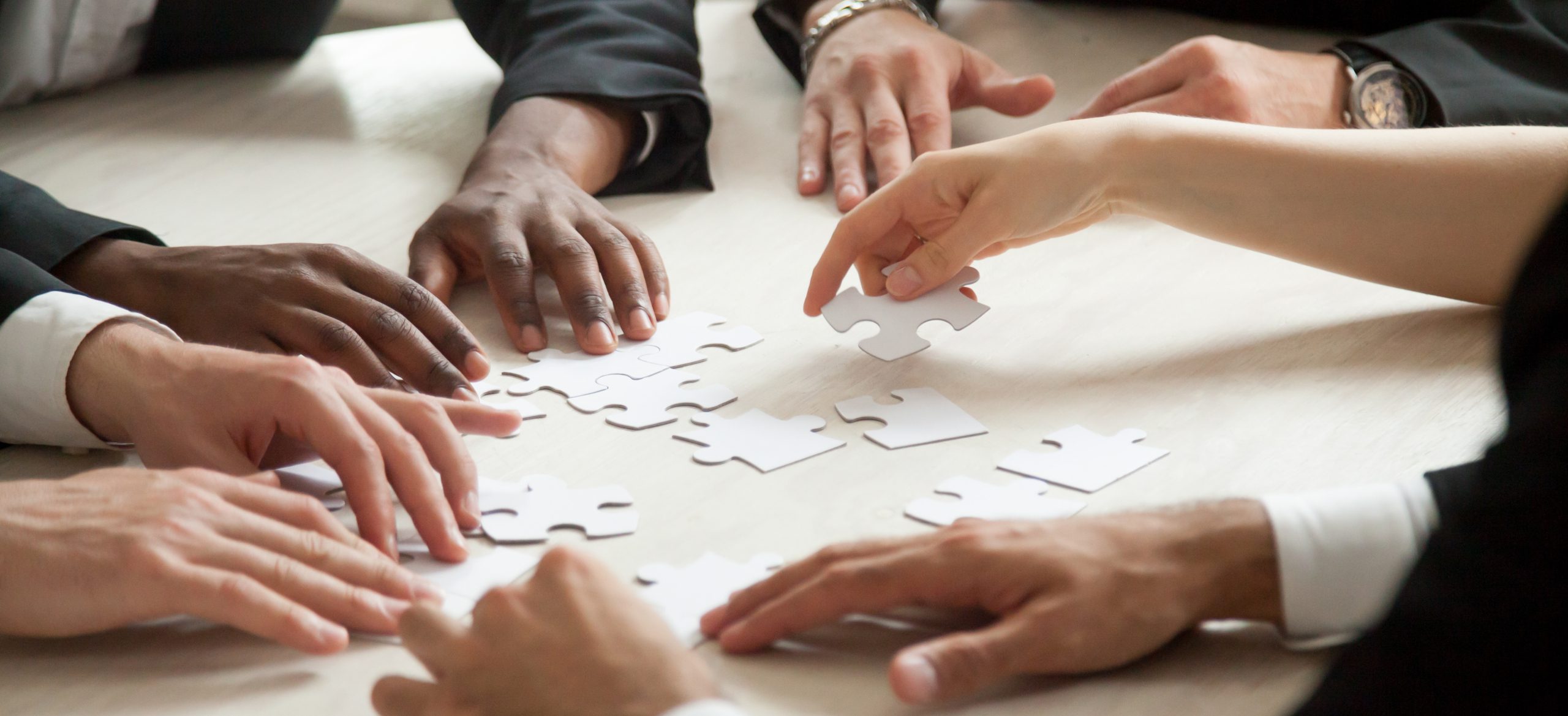 Close up of multiethnic team solving blank puzzle game.