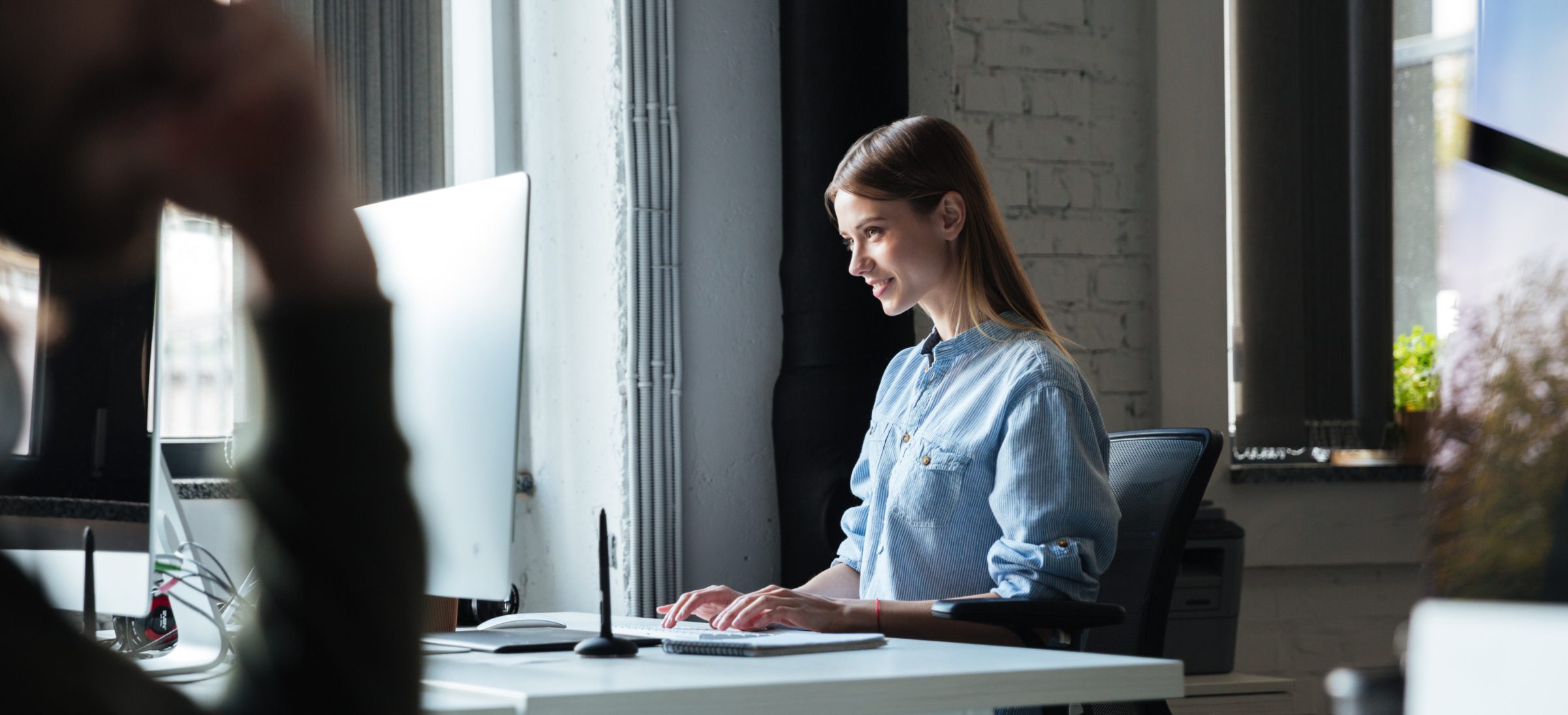 Woman work in office using computer. Looking aside.